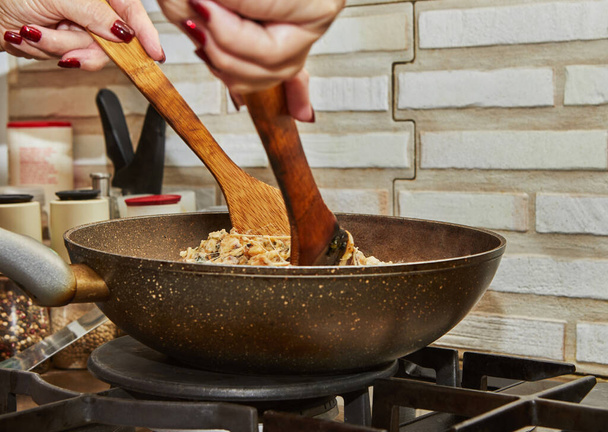 Šéfkuchař míchá s dřevěnými stěrkami v pánvi se smaženými brambory, kaštany, petrželí, parmezánem na plynovém sporáku. Krok za krokem recept - Fotografie, Obrázek