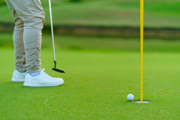 Golfista przygotowuje się do piłki golfowej putt na zieleni podczas pola golfowego - Zdjęcie, obraz