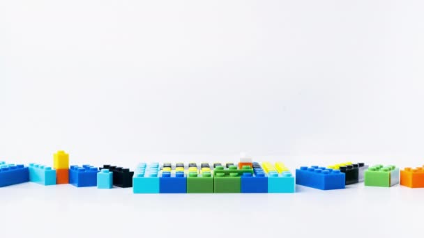 Stop animacji ruchu domów Lego są zbudowane z różnych kolorowych bloków na białym tle. Czas procesu budowy upływa z klockami LEGO. - Materiał filmowy, wideo