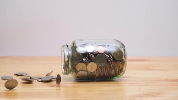 スローモーションでは、コインは木製のテーブルの落下ガラス瓶から滑りました。金融の概念. - 映像、動画