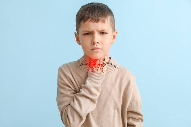 Ill little boy with pain in throat on light blue background - Foto, Imagem
