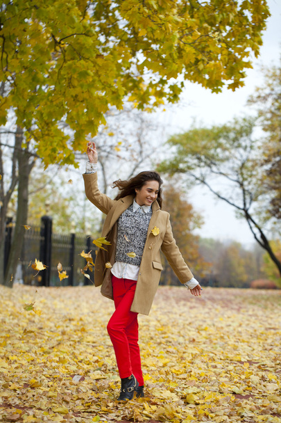 Young woman in fashion coat walking in autumn park - 写真・画像