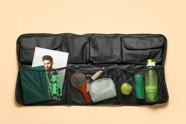Travel organizer with different things, bottles of drink and apple on color background - Photo, Image