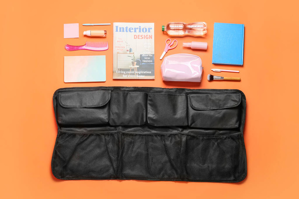 Travel organizer with cosmetics, stationery and bottle of water on color background - Foto, imagen