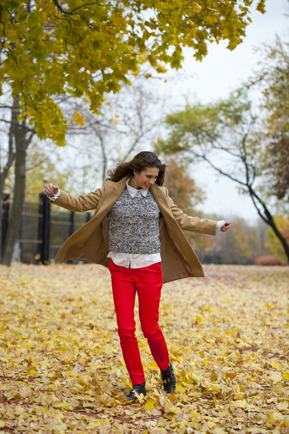 Young woman in fashion coat walking in autumn park - Fotoğraf, Görsel