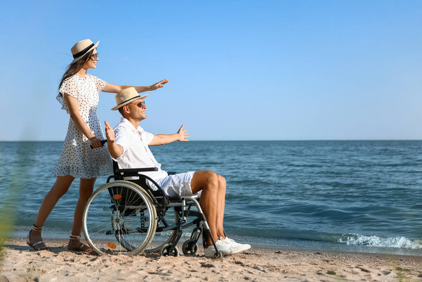 Happy man with physical disability and his girlfriend at sea resort - 写真・画像