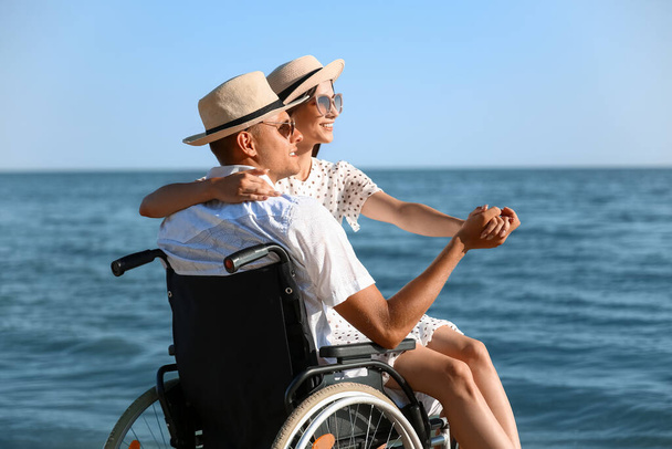Νεαρός με σωματική αναπηρία και η κοπέλα του στο παραθαλάσσιο θέρετρο - Φωτογραφία, εικόνα