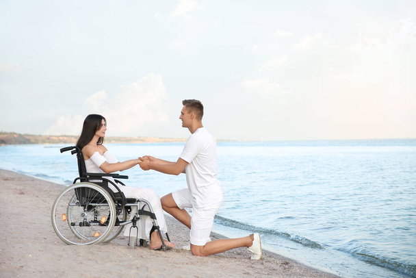 Gelukkige vrouw met lichamelijke handicap en haar vriend op zee resort - Foto, afbeelding