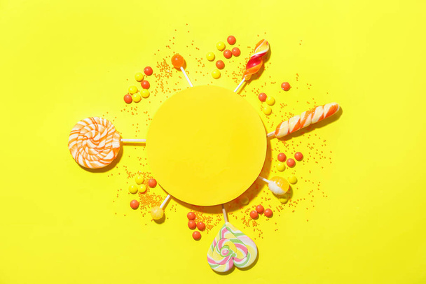 Composition with blank card, lollipops and candies on yellow background - Foto, Imagen