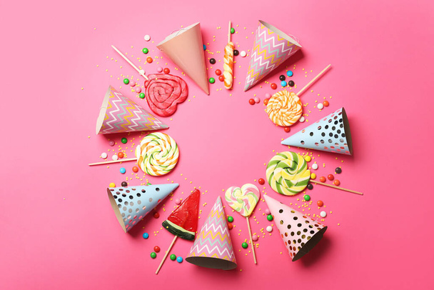 Frame made of sweet lollipops and birthday hats on color background - Фото, изображение