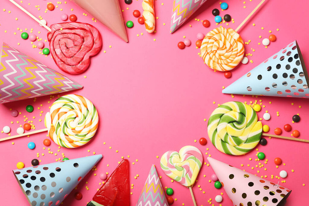 Frame made of sweet lollipops and birthday hats on color background, closeup - Photo, Image
