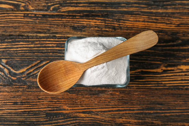 Bowl of baking soda and spoon on wooden background - Photo, Image