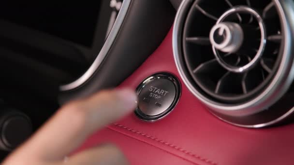 La mano del guidatore preme il pulsante per avviare il motore dell'auto. Avviamento senza chiave del motore. Concetto di trasporto e tecnologia - Filmati, video