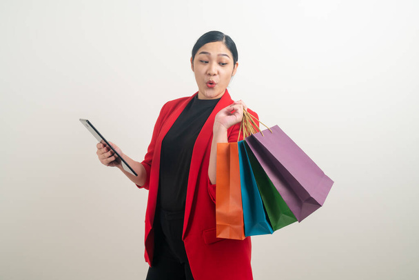 Asian woman holding shopping bag and tablet on hand with white background - Foto, immagini