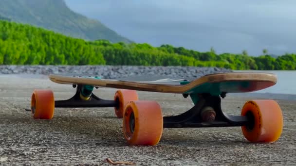 Nastolatek jeździ longboard wzdłuż pięknej drogi z zielonymi palmami - Materiał filmowy, wideo