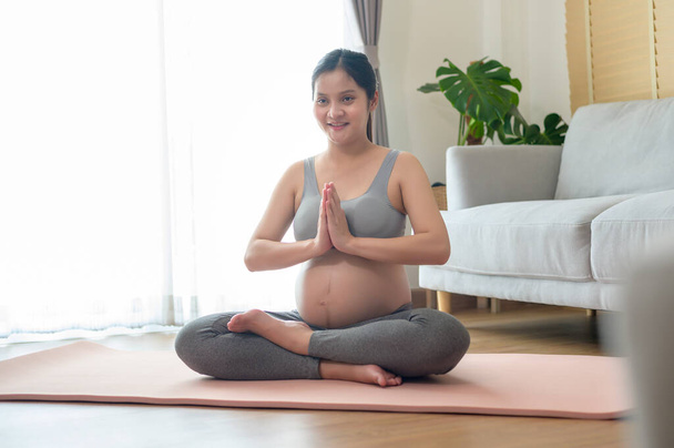 Mujer embarazada joven haciendo yoga en el hogar, cuidado de la salud y el embarazo concepto de cuidado - Foto, imagen