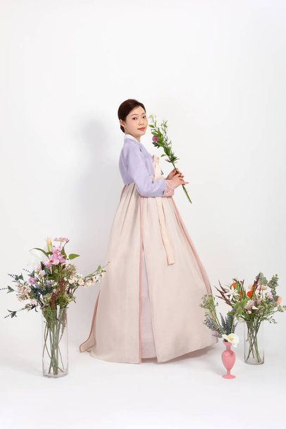 spring beauty concept, beautiful korean woman wearing hanbok with flowers - Fotó, kép