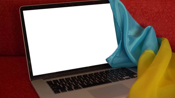 der leere Laptop-Bildschirm auf dem Hintergrund der Flagge der Ukraine. Kopierraum - Foto, Bild