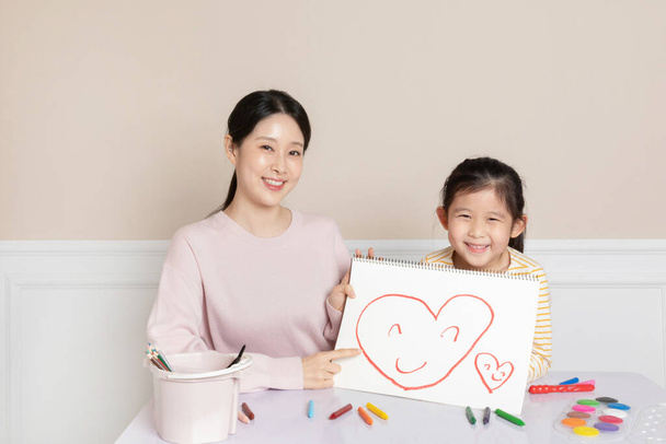 Asian Korean daughter holding a sketchbook with a heart on it - Zdjęcie, obraz