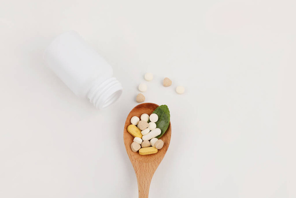 a wooden spoon and a pills, white background, medical creative concept photo - 写真・画像