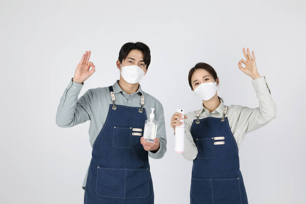 Asian Korean young man and woman startup concept holding disinfectant and gesturing OK - Фото, изображение