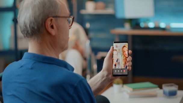Hombre jubilado hablando con la familia en videoconferencia en línea - Foto, Imagen