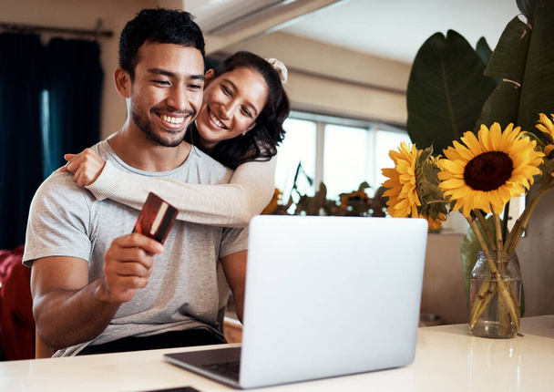 Theres a massive discount on that holiday we wanted to go on. Shot of a man holding a credit card and using his laptop while at home with his girlfriend. - Foto, Imagen