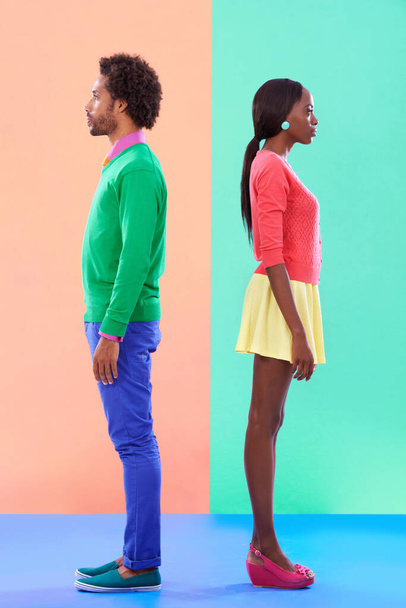 Not quite complete opposites. Studio shot of a young couple standing against a colourful background. - Foto, afbeelding