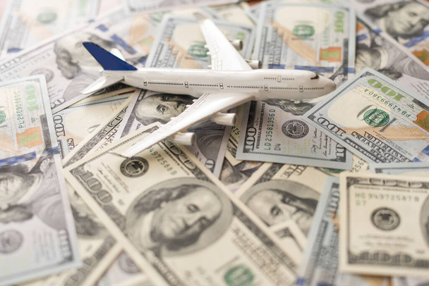 Background of one hundred dollar bills with model airplane on flat lay design to travel concept. - Fotó, kép