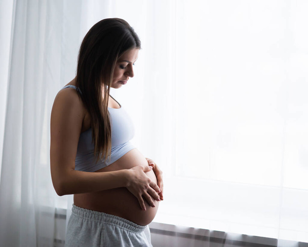 La giovane donna incinta sta riposando a casa e aspetta un bambino. Gravidanza, maternità, assistenza sanitaria e stile di vita. - Foto, immagini