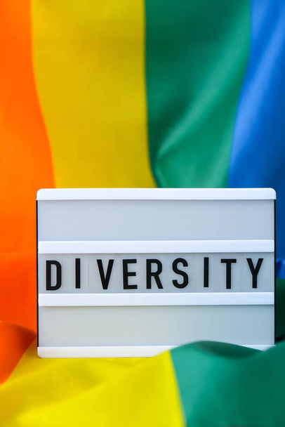 Regenboogvlag met lichtbak en tekst DIVERSITY. Rainbow lgbtq vlag gemaakt van zijde materiaal. Symbool van LGBTQ trots maand. Gelijke rechten. Vrede en vrijheid - Foto, afbeelding