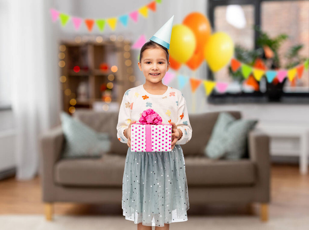 smiling girl in party hat with birthday gift - Фото, зображення