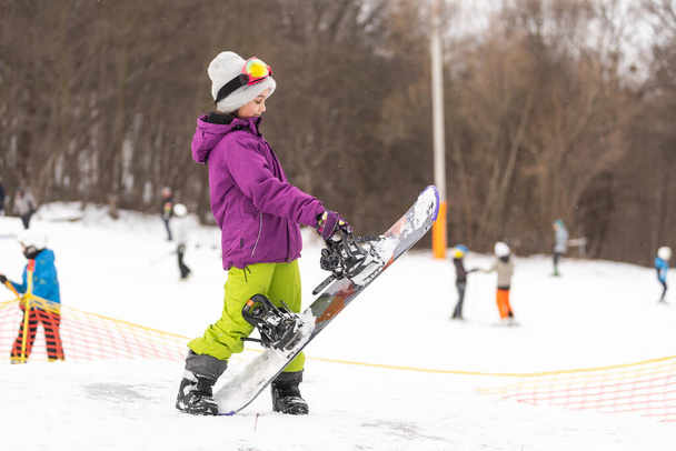 Snowboard winter sport. Cute girl with snowboard going to slide in winter nature - Zdjęcie, obraz
