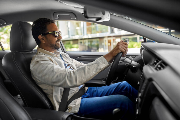 smiling indian man in sunglasses driving car - Foto, Imagen