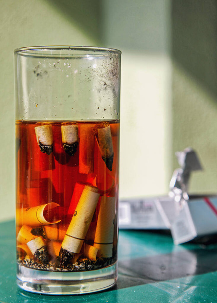 Сигарети в попільничці зі скла з водою
 - Фото, зображення