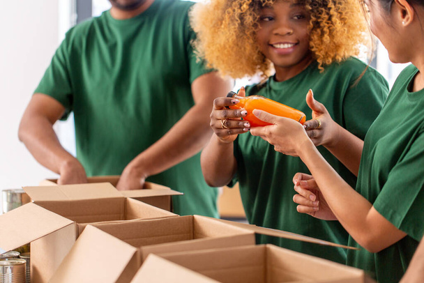 close up of volunteers packing food in boxes - 写真・画像