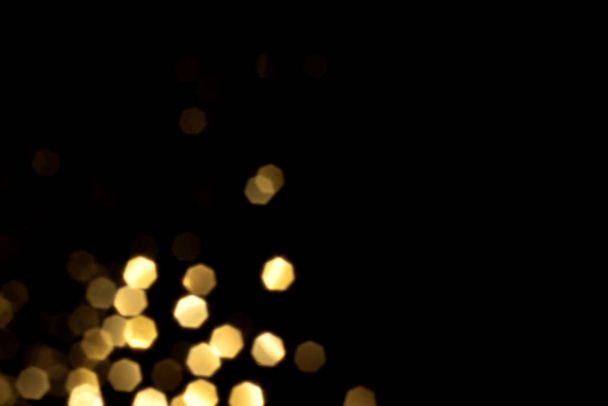 Golden blurred bokeh lights on black background. Glitter sparkle stars for celebrate. Overlay for your design - Foto, afbeelding