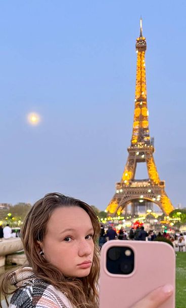 a teenage girl stands against the backdrop of the Eiffel Tower, it is possible to use it for some kind of advertising for a travel company - Foto, imagen