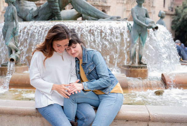 Valencia 'da bir çeşmede oturan genç İspanyol lezbiyen çift - gay ve lezbiyen konsepti - Fotoğraf, Görsel