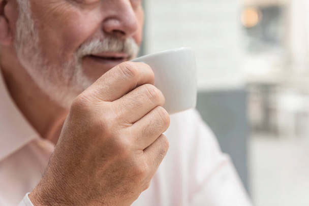 the close-up of an unrecognizable older man holding a cup of coffee or tea - Fotoğraf, Görsel