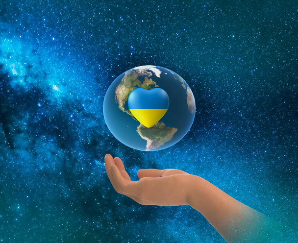 Země zeměkoule s Ukrajinou vlajka barva modrá a žlutá v srdci symbol v rukou na přední modré hvězdné nebe mlhoviny držet světový mír koncept příroda pozadí - Fotografie, Obrázek