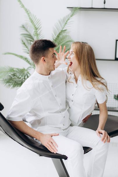 Deux jeunes dentistes en blouse blanche s'amusent dans la chaise du patient - Photo, image