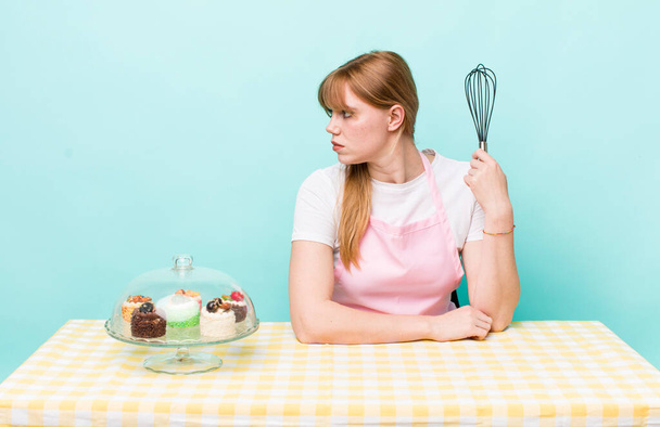 red head pretty woman on profile view thinking, imagining or daydreaming. home made cakes concept - 写真・画像