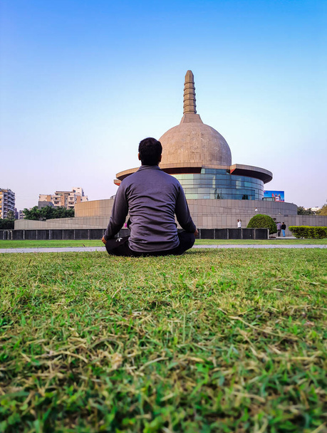 young man meditating at buddha stupa with bright blue sky at morning from different angle image is taken at buddha park patna bihar india on Apr 15 2022. - Foto, imagen