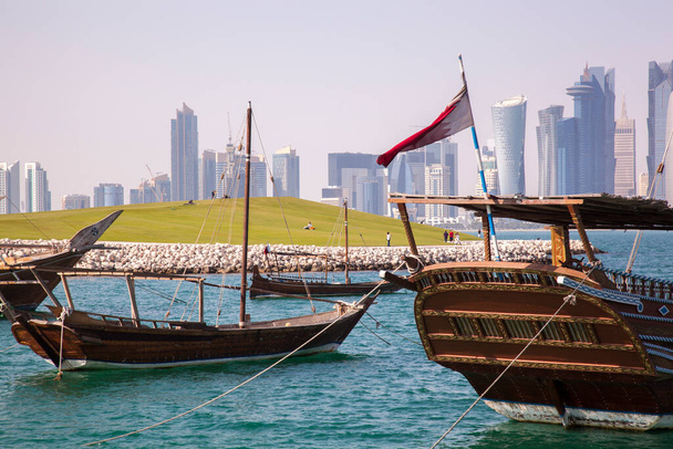 Doha, Qatar- 24 april 2022: Traditionele dhow boten met de futuristische skyline van Doha op de achtergrond. - Foto, afbeelding