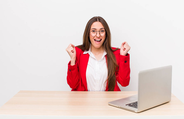 hispanic pretty woman feeling shocked,laughing and celebrating success.  business and desk concept - Fotó, kép