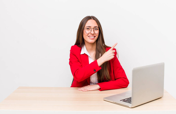 hispanic pretty woman smiling cheerfully, feeling happy and pointing to the side.  business and desk concept - Фото, зображення