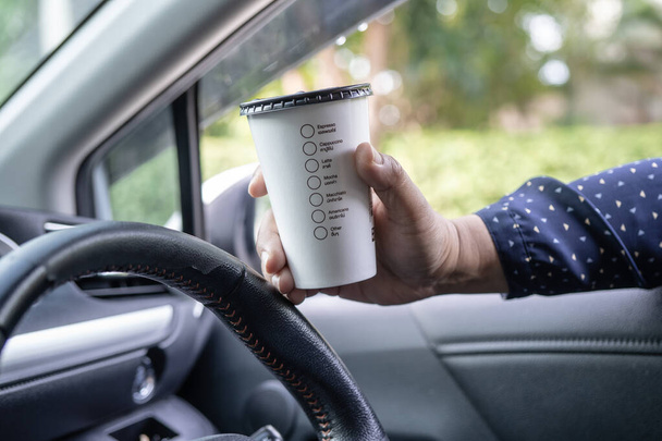 Aasialainen nainen tilalla kuuma kahvi kuppi ruokaa juoda autossa, vaarallinen ja riski onnettomuus. - Valokuva, kuva