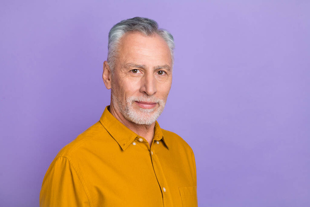 Photo of struct elder grey hairdo man wear yellow shirt isolated on violet color background - Foto, imagen