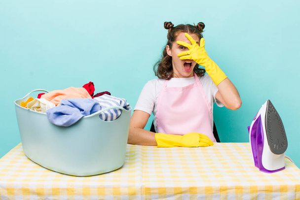 young pretty woman  looking shocked, scared or terrified, covering face with hand. house work concept - Foto, imagen